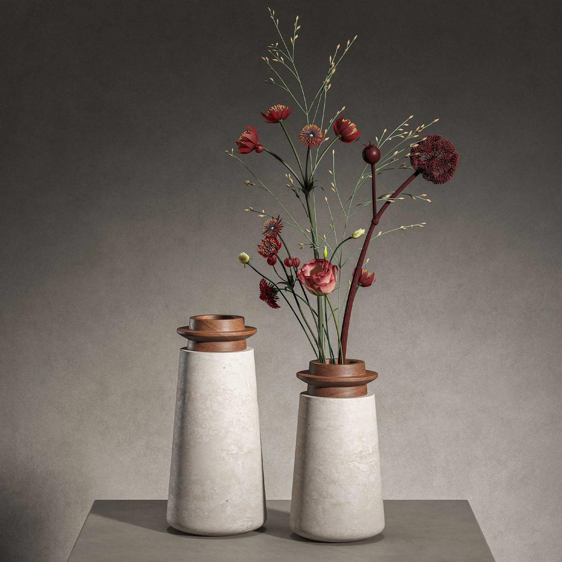 Two Tivoli vases in Travertino Navona marble with Walnut wood top. Large size (left) and Small size (right) with gray background on a gray tabletop. Small vase has red and green flowers in it that reach the top of the image. 